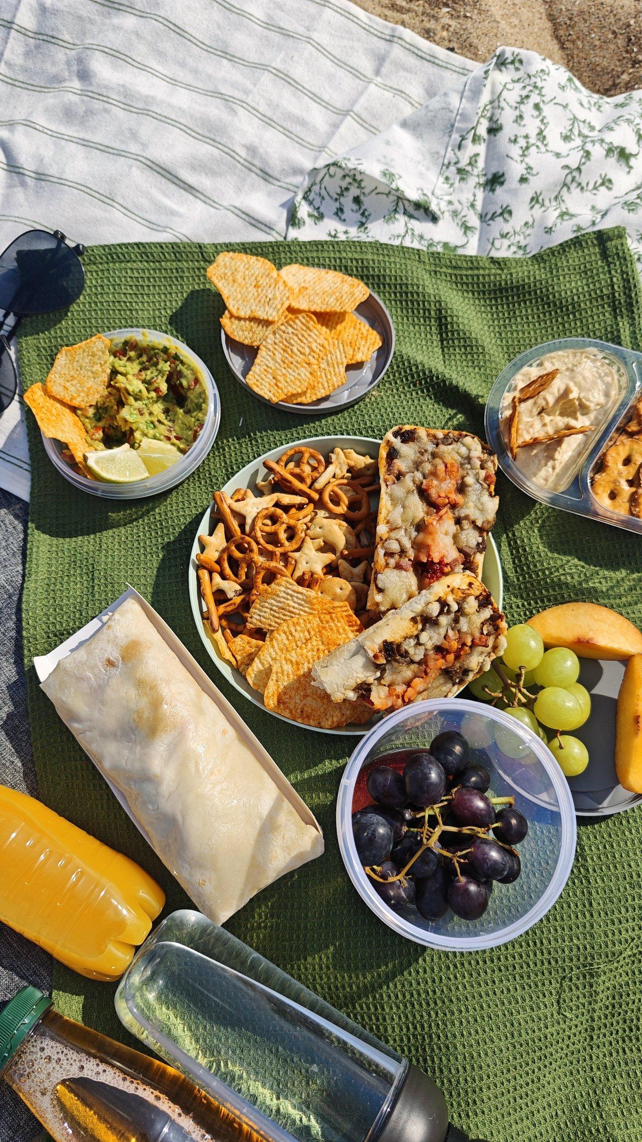 Assortiment coloré de summer picnic snacks : fruits, sandwiches et conserves pour un pique-nique estival sans frigo.