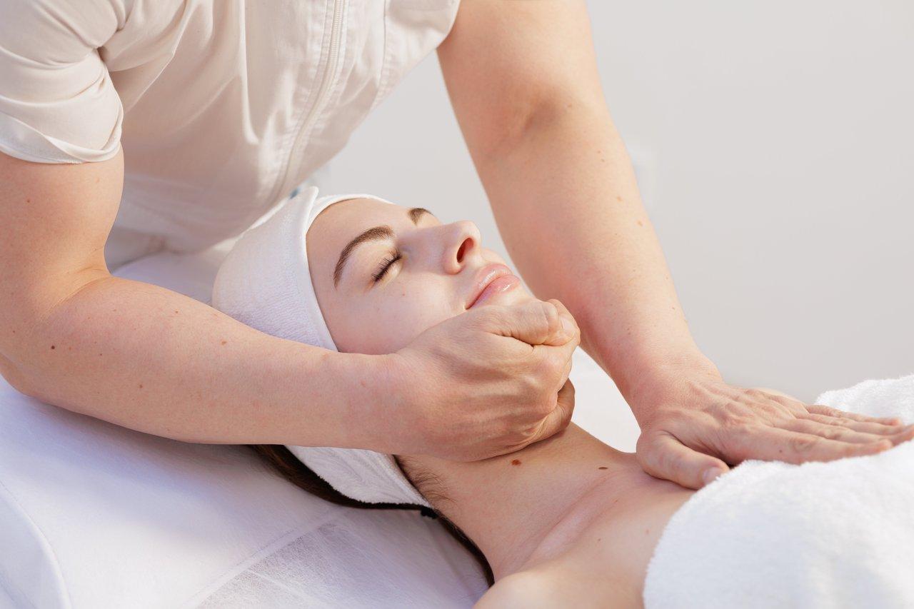 Automassage du visage au réveil sous une lumière naturelle, favorisant relaxation et bien-être matinal.