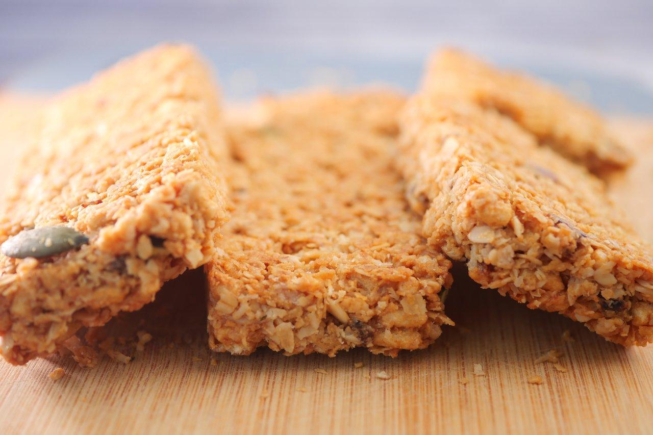 Barres de céréales maison, saines et croustillantes, préparées avec des ingrédients naturels sur une planche en bois.
