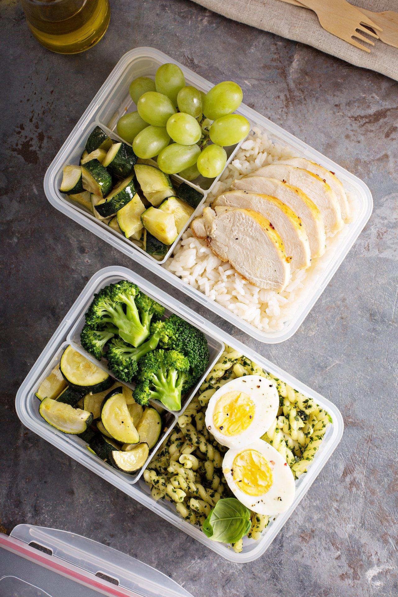 Containers de préparation de repas sains avec poulet, riz, œufs, pesto, courgettes et brocoli pour un batch cooking efficace.