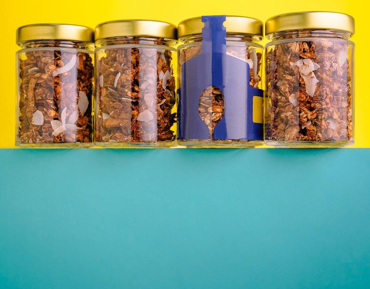 Étagère d'encas bio pour enfants avec des bocaux de granola et flocons de noix de coco.