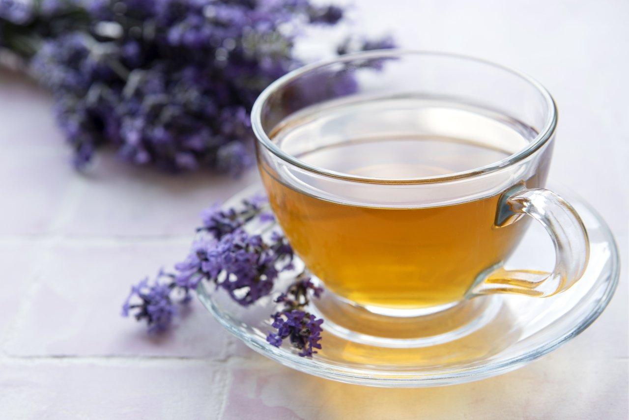 Infusion de tisane à la lavande près d’une fenêtre, idéale pour une soirée relaxante avec un roll-on lavender.