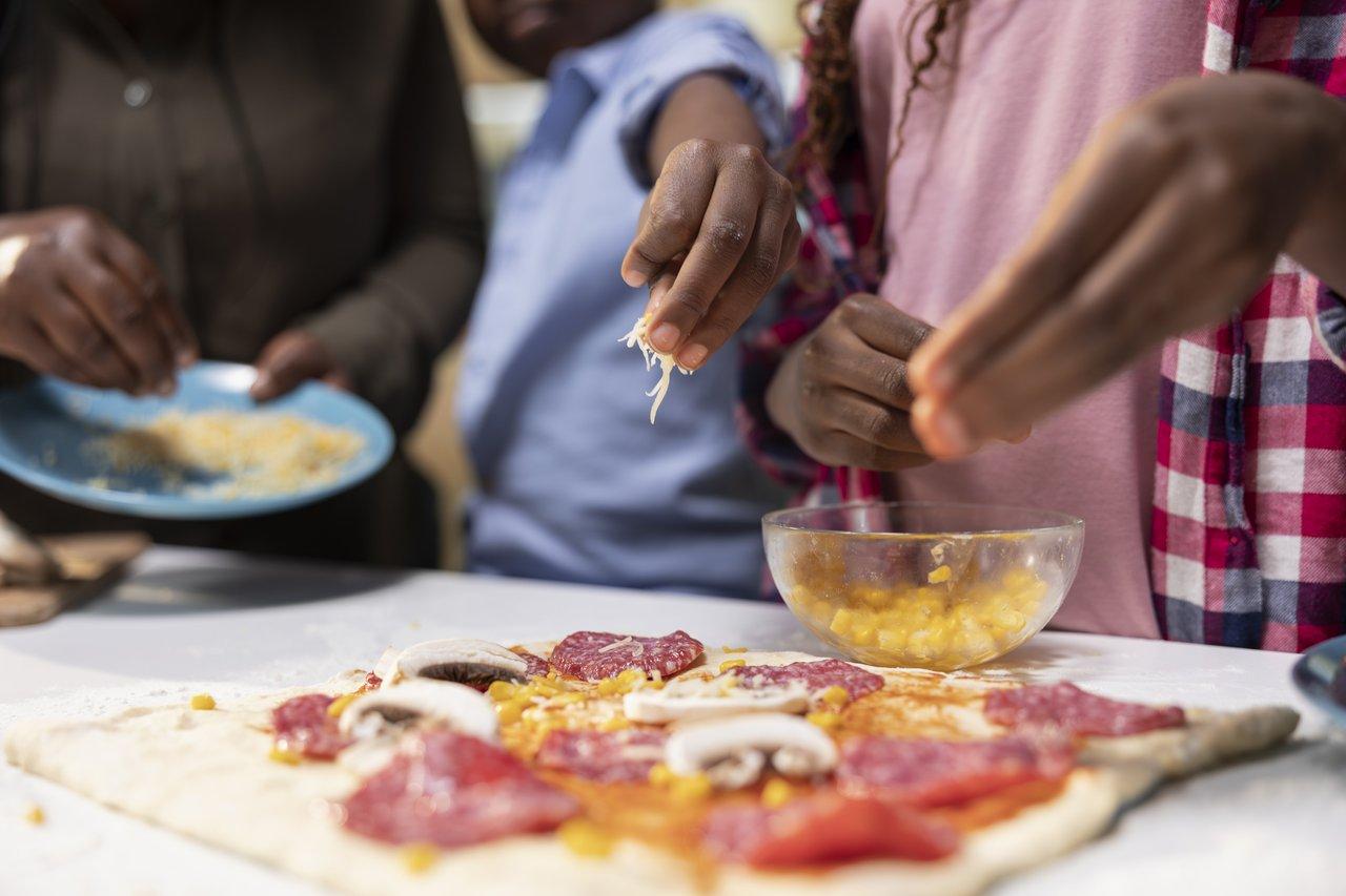 Mini-pizza maison pour enfants, garnie de mozzarella râpée sur une assiette colorée, idéale pour un encas équilibré.