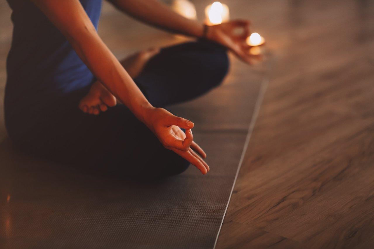 Moment de détente en soirée : femme méditant dans une posture de yoga pour réduire la charge mentale.