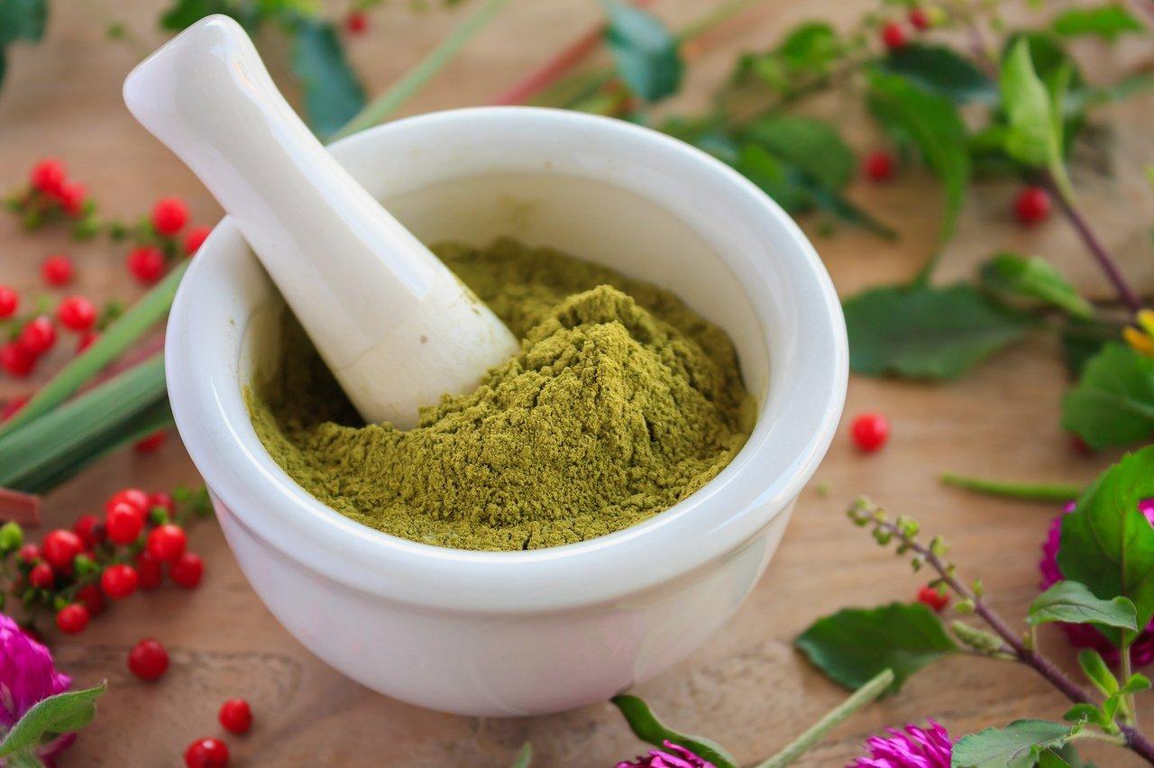 Poudres d'herbes adaptogènes en harmonie dans un mortier pour renforcer la vitalité naturellement.