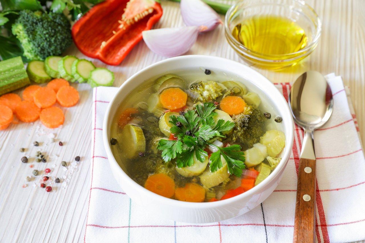Soupe de légumes fumante avec ustensiles en bois, idéale pour un hiver sain et réconfortant.