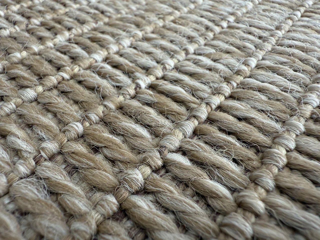 Tapis en fibres naturelles superposés, alliant sisal, jute, chanvre et coton pour un salon lumineux et écologique.