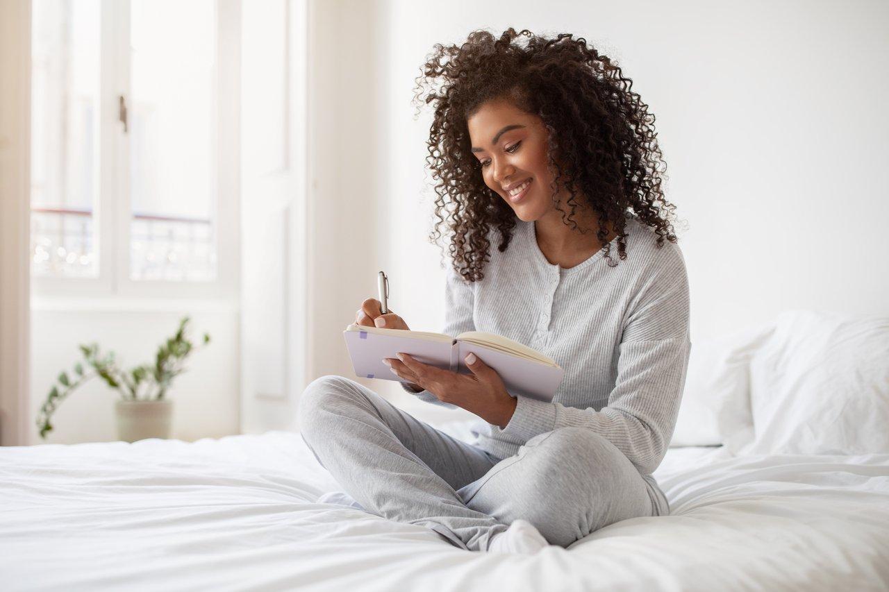 Une femme hispanique rédige sa checklist de bien-être mental pour diminuer la charge mentale du soir.