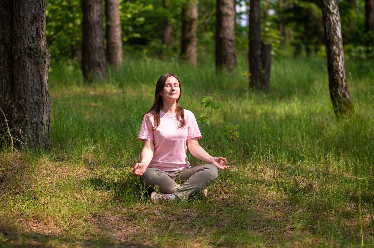 Une femme méditant en pleine nature au printemps, illustrant la pratique du mindfulness pour booster son énergie.