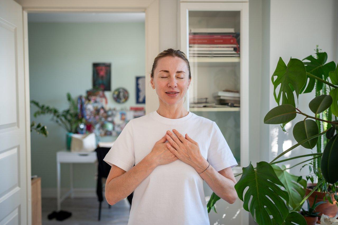Une femme pratiquant la respiration en carré pour apaiser l’esprit avant de dormir dans une chambre calme.
