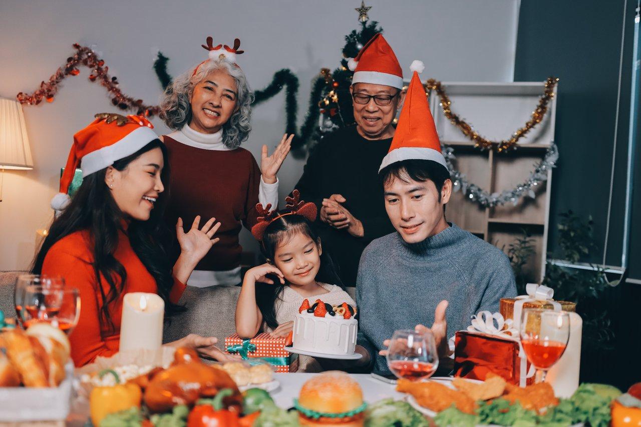 Une festive family gathering chaleureuse avec plusieurs générations partageant des cadeaux à la maison.