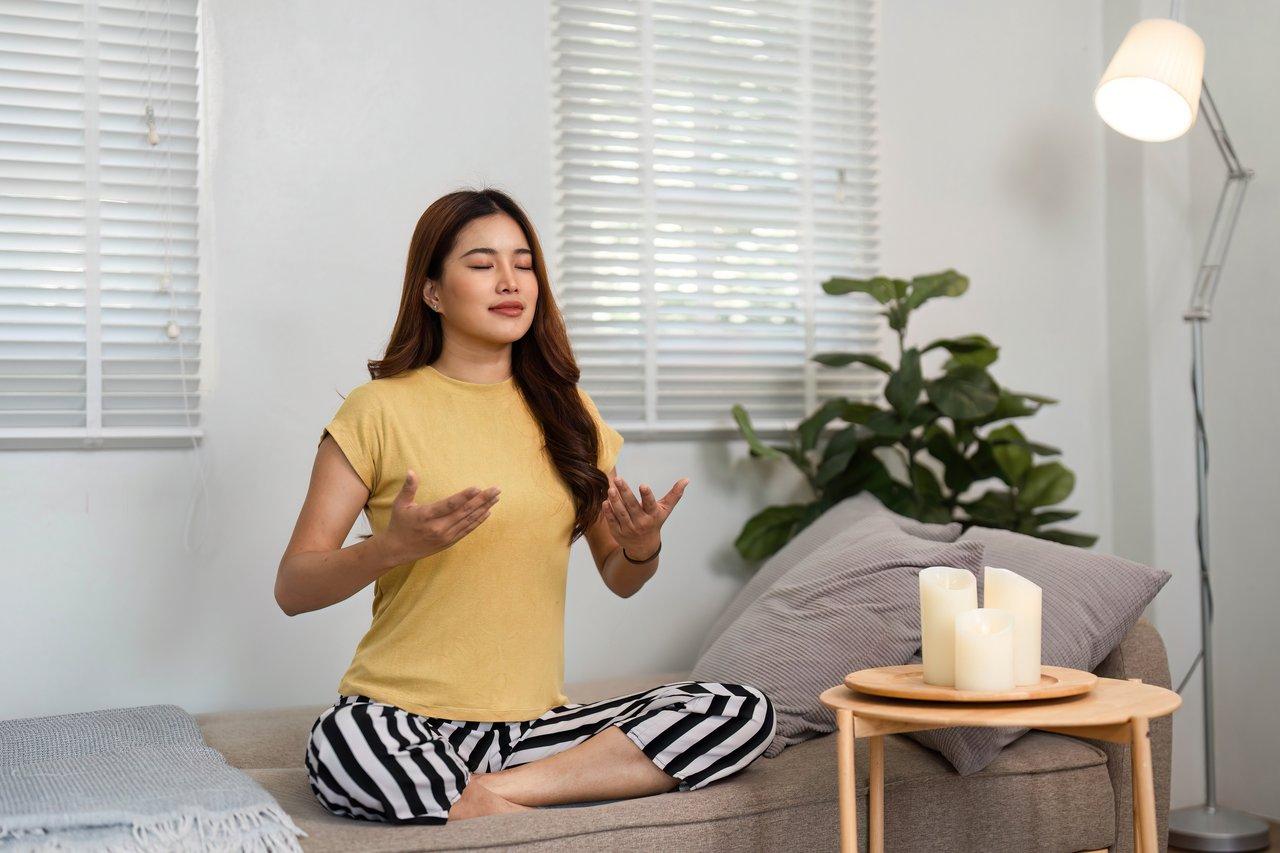 Une personne méditant dans un meditating calm room, ambiance zen et huiles essentielles pour lutter contre le stress hivernal.