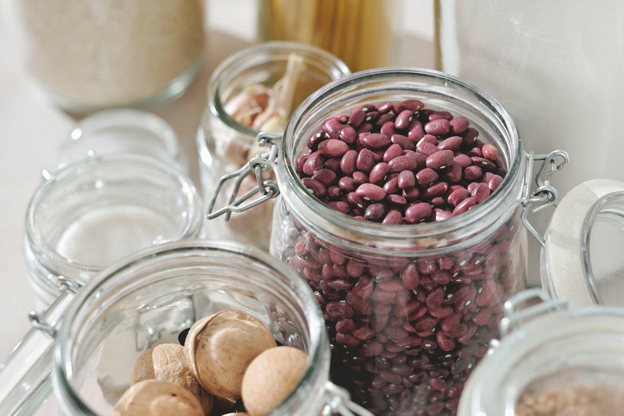 Une sélection de healthy pantry essentials : eau, huile d’olive, quinoa et beurre de cacahuète.